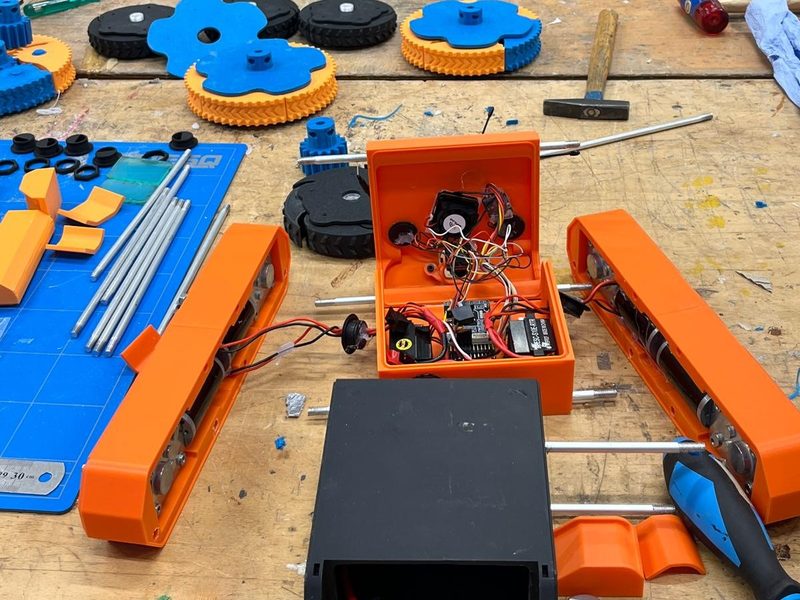 3D-printed parts, wheels and tools laid out on a workbench during assembly