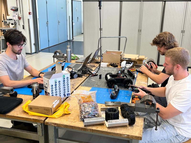 Three UNAMIQ engineers assembling electronics at a workbench